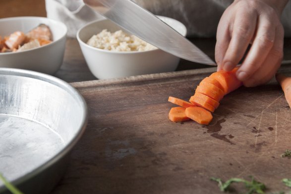 Osoba przyrządzająca potrawę kroi marchewkę w plastry z pomocą ostrego noża